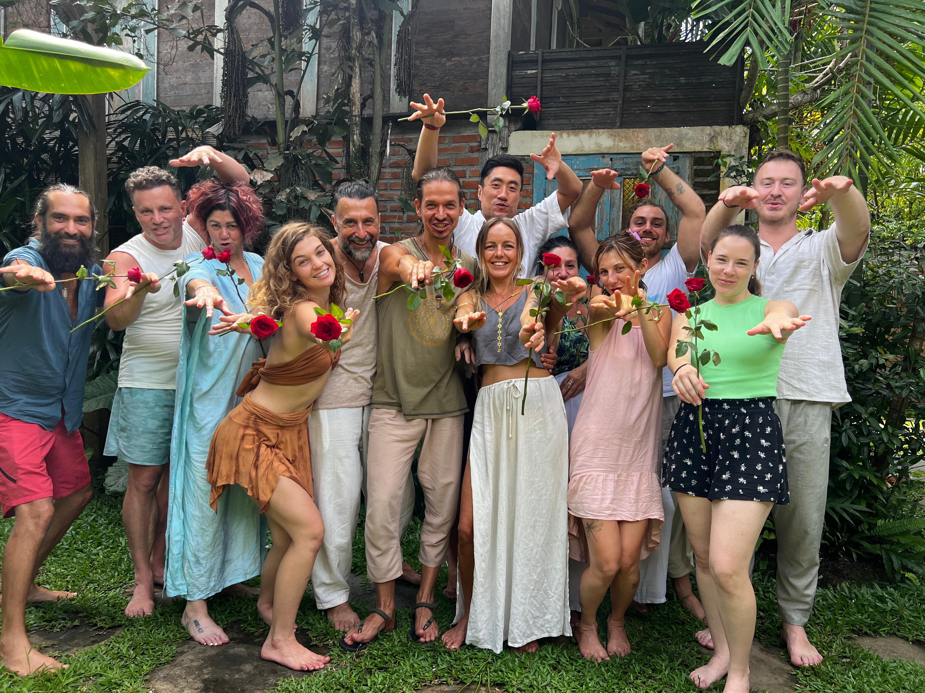 Retreat participants gathered in a garden, smiling and reaching toward the camera with red roses in hand