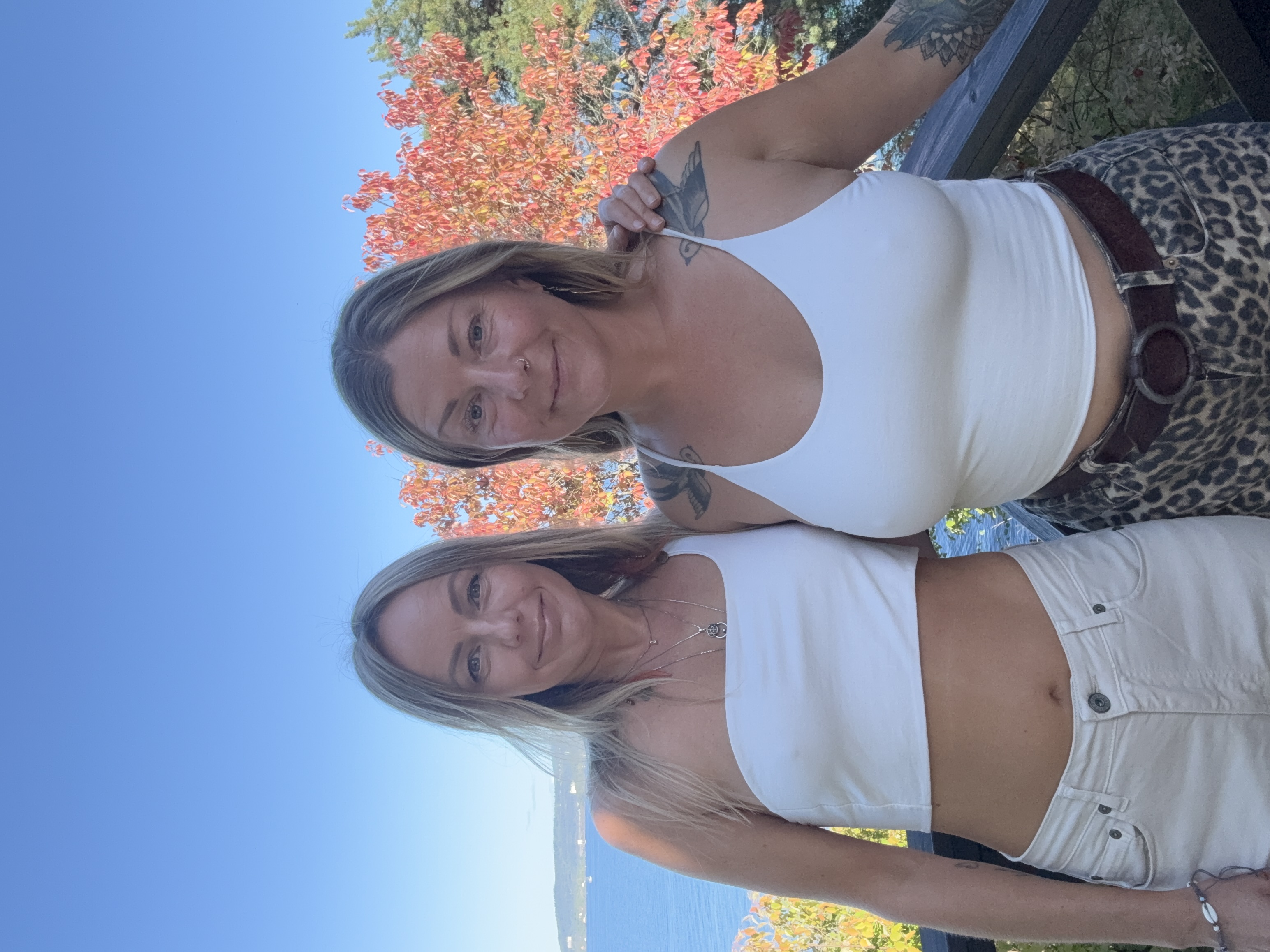 Lina and Linn standing together on a balcony above the Oslofjord, framed by autumn leaves